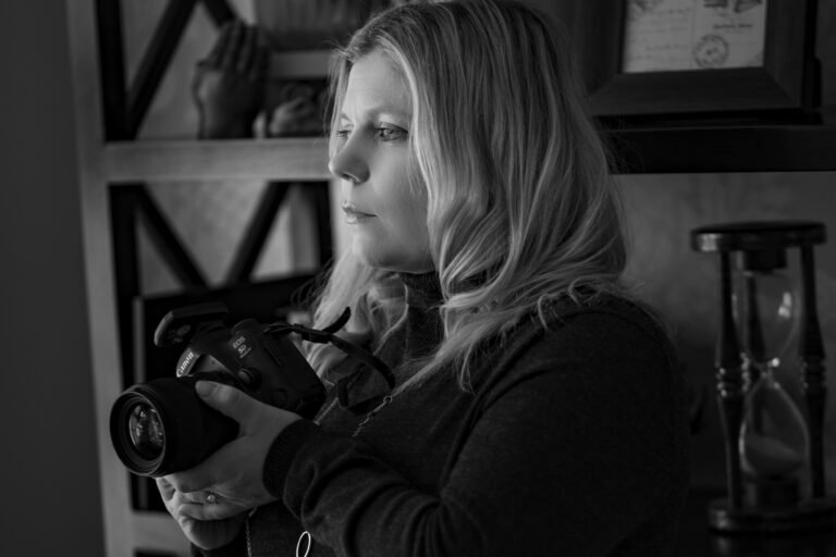 Profile image of Emma Lowe, Professional Photographer with camera in hand - black and white.