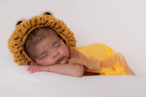 Cute sleeping newborn with yellow wrap and cute lion bonnet