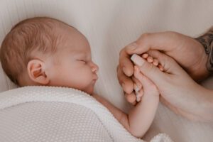 Baby with Mother and Father holding the newborns hand